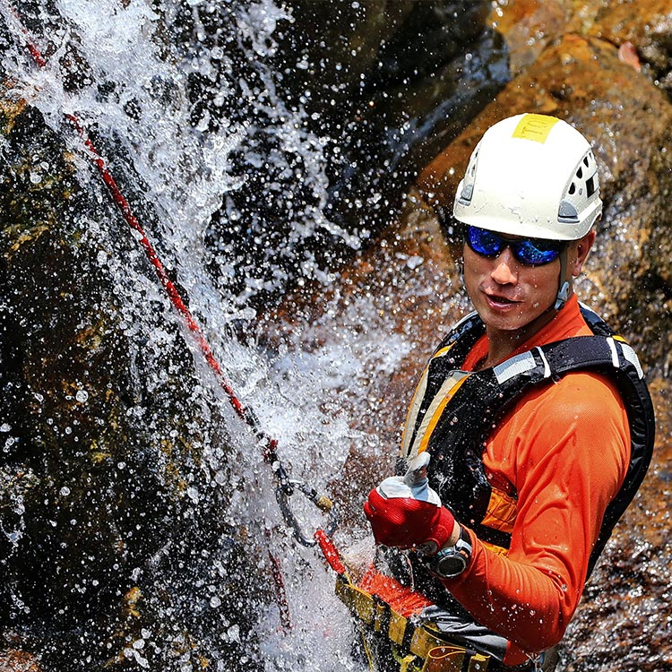 A Young Foreign Boy, in Orange, with a thumbs up, Ready to Witness the Delight of Waterfall Abseiling