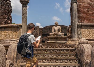 A foreigner climbing the steps that lead to the ancient Buddha statue, and the ruins at the Sacred Quadrangle, from the Ancient City of Polonnaruwa