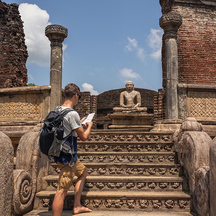 A foreigner climbing the steps that lead to the ancient Buddha statue, and the ruins at the Sacred Quadrangle, from the Ancient City of Polonnaruwa