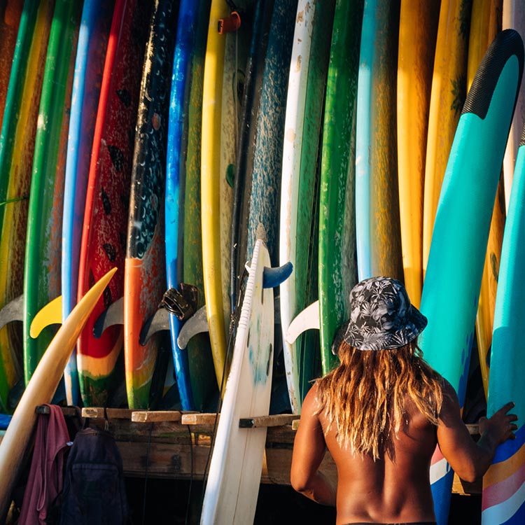 A Man trying to choose a paddleboard from a stack at Weligama, Sri Lanka