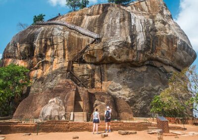 Two foreigners standing in front of the gigantic Sigiriya Rock Fortress that stands with Majesty