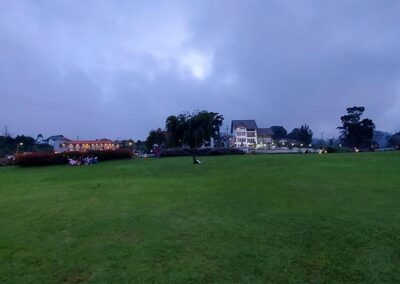 The greenish lawn and the far away illuminated buildings at the beautiful Victoria Park at Nuwara Eliya