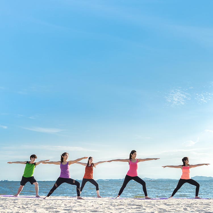 A group of women practicing yoga on a beach