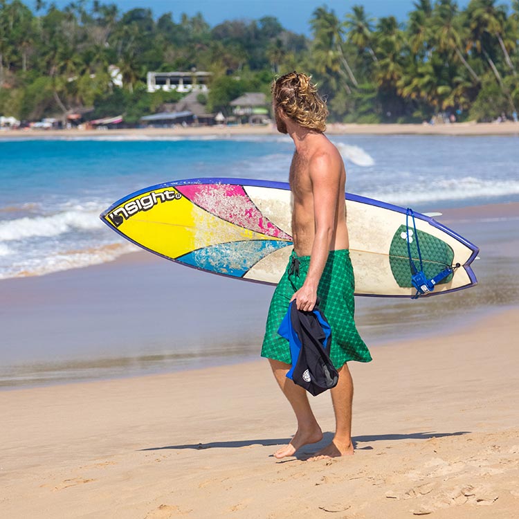 A Young Foreigner with a SurfBoard walking on the sandy shores of Unawatuna, Sri Lanka