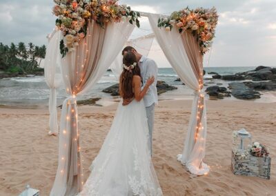 A Young Couple in Wedding Attire kissing each other at a Beach Wedding Ceremony at Sri Lanka