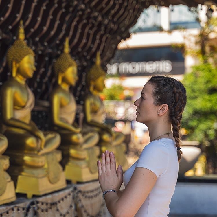 A Foreign Lady Worshipping the golden Buddha statues at Gangaramaya Temple