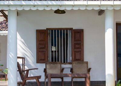 A white colour Village House of Sri Lanka with a few chairs in front of it.