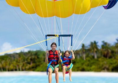 An elder brother and a younger sister enjoying parasailing over the ocean