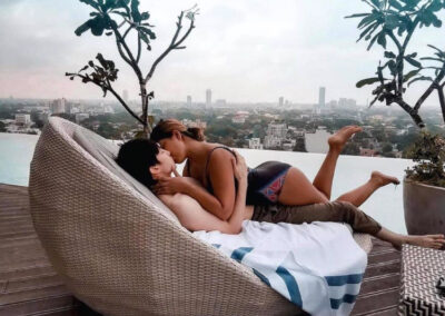 A Couple in swimwear kissing each other while relaxing on a comfy sofa by a swimming pool during their honeymoon in Sri Lanka