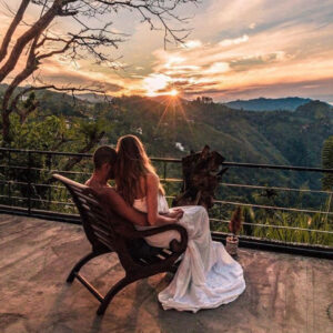 A Couple seated on a balcony, witnessing the beauty of a sunrise. during their honeymoon in Sri Lanka
