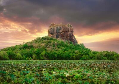 The Sigiriya Rock Fortress Standing with Grandeur amidst the verdant surroundings and the lake at the time of sunset