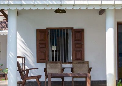 Three wooden chairs in front of a white wall at a Sri Lankan Village House