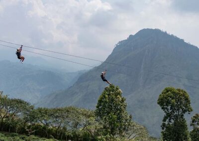 Two people enjoying zip lining in a background filled with greenery