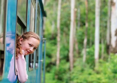 A girl peeping out of the window enjoying the beauty around during a Train Ride from Nuwara Eliya to Ella