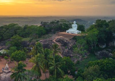 The greenery, rocks, and the white buddha statue in the ancient city of Anuradhapura