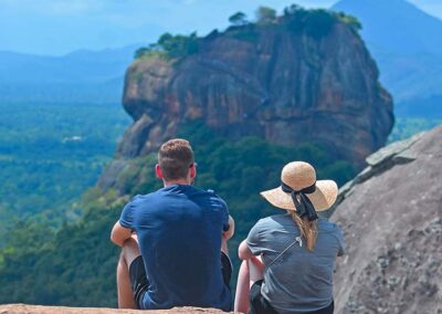 A foreign couple on the top of the Pidurangala rock staring at the Sigiriya Rock Fortress