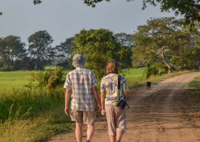 A Foreign Couple walking on a gravel road through the greenery enjoying a Village Walk